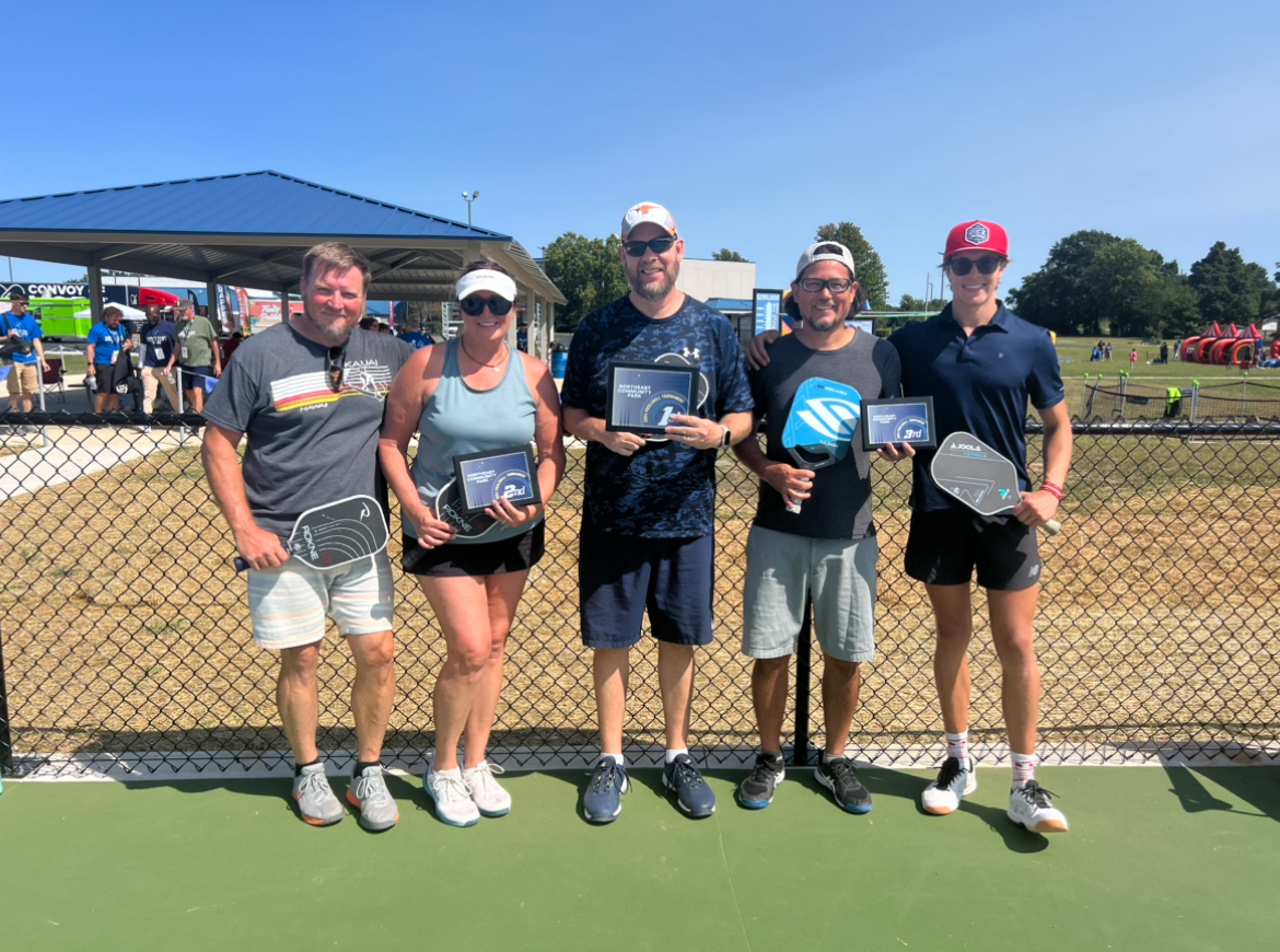 Tournament medalists holding paddles and plaques on outdoor courts