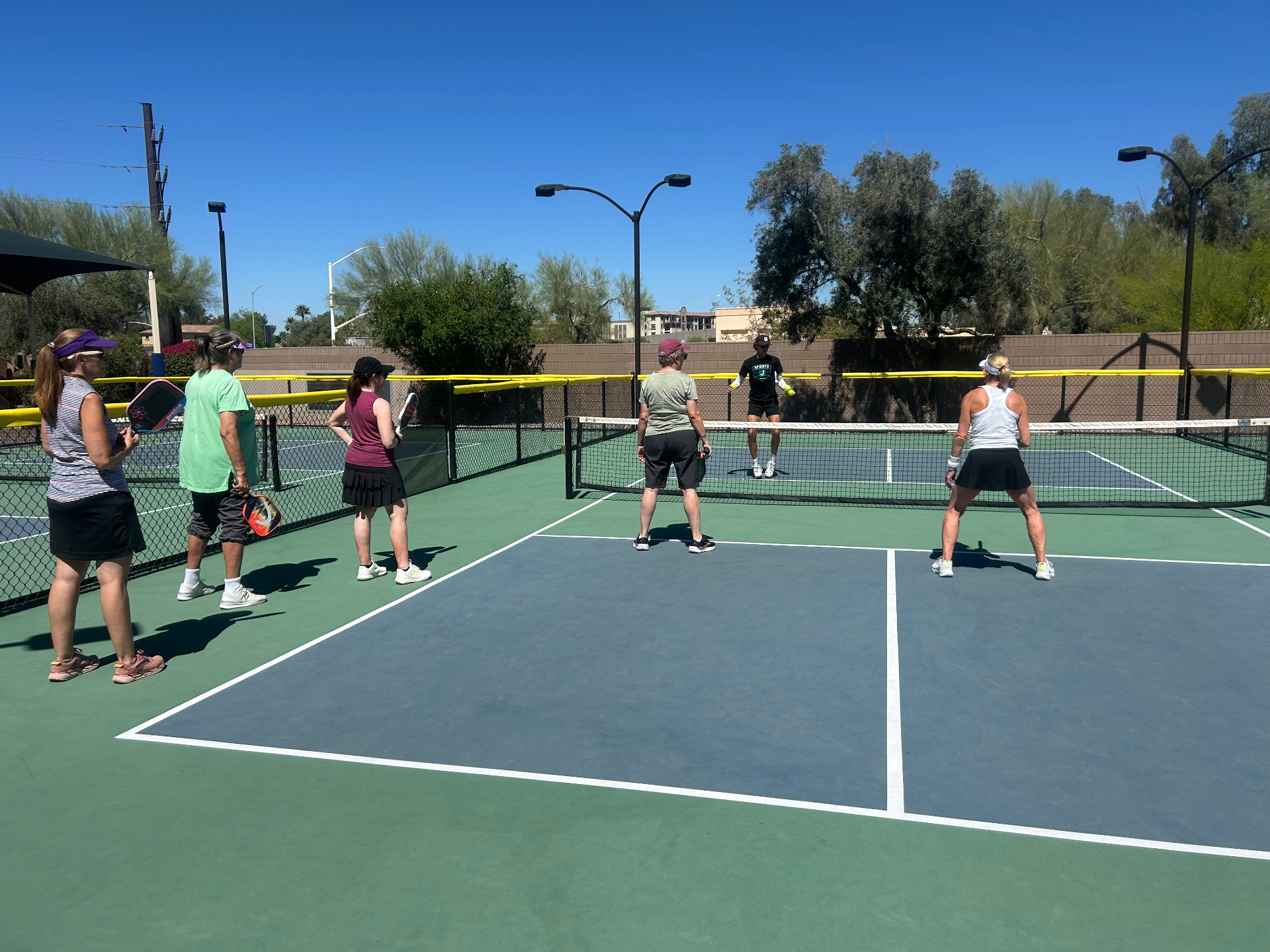 Group clinic on sunny outdoor pickleball courts